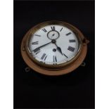 A small antique circular brass and metal ships clock. enemaled dial