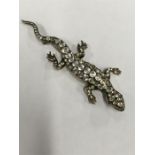 A french silver lizard brooch encrusted with white stones.