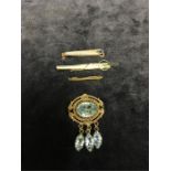 Three gold tie clips and a brooch set with blue stones.