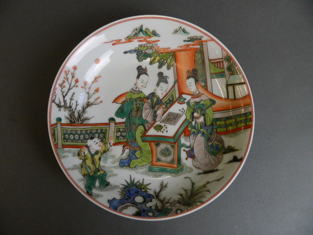 A Chinese famille verte enamelled porcelain dish decorated with women playing board games in a