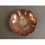 A copper petal shaped trinket bowl set with a silver George VI 1944 1 rupee coin, 4" diameter