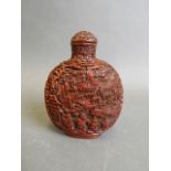 A finely carved cinnabar lacquer snuff bottle decorated with a village scene and figures, 4" high (