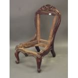 An early Victorian rosewood nursing chair with carved and pierced crest back, raised on carved