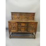 A 1930s Jacobean style oak sideboard with end cupboards flanking two drawers and canteen drawer,