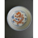 A Chinese blue and white porcelain dish with iron red enamelled dragon and flaming pearl decoration,