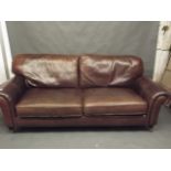 A Contemporary leather sofa with scroll arms, raised on turned support, 90" long