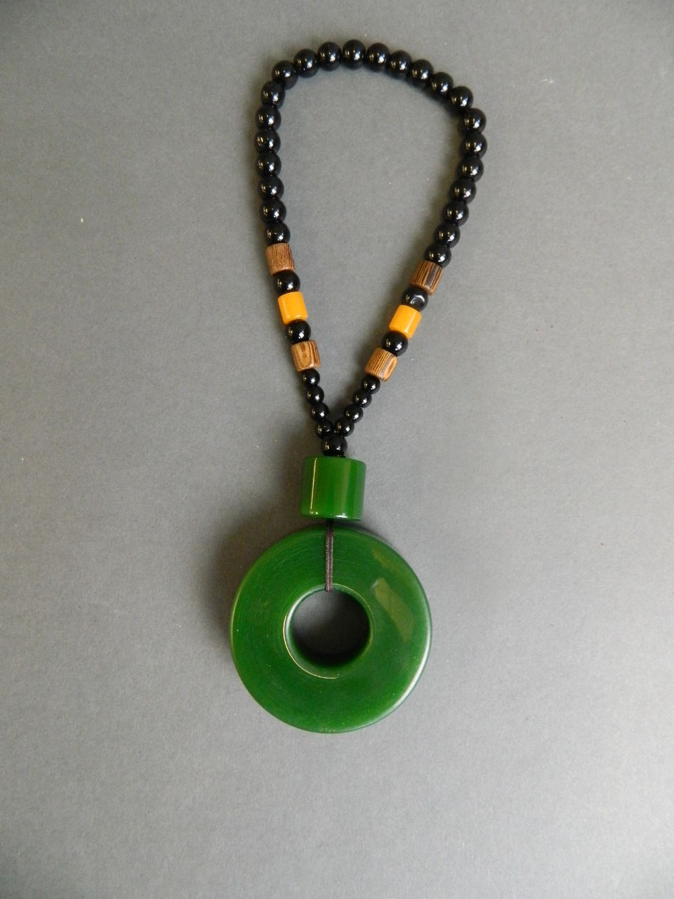 A Chinese spinach jade pi-disc pendant on a black bead string, pendant 2½"