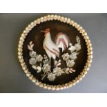 A basket work and shell plaque depicting a cockerel amongst flowers, 14" diameter