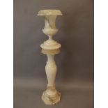 A pink alabaster pedestal with reeded column and acanthus leaf carving, with matching pedestal