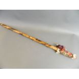 An Ethnic hardwood walking stick with wool work wrapped handle adorned with shells and tassels,