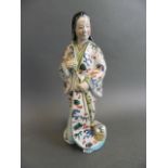 A Chinese porcelain figure of a lady in a flowing robe decorated with flowers and symbols in