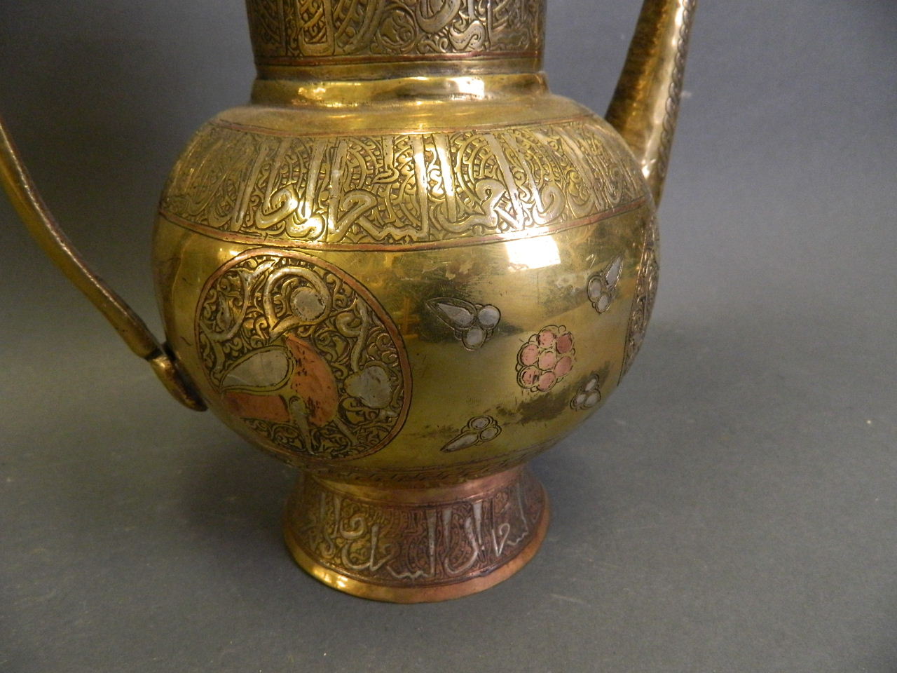 An Islamic polished brass water pot with silver and copper inlaid decoration, 10½" high - Image 2 of 2