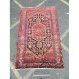 A hand woven Persian Hamadan Luri carpet with all over design on a red field, 55" x 93"