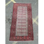 An antique Afghan Belouche tribal rug with a red and ebony border, 36½" x 72"