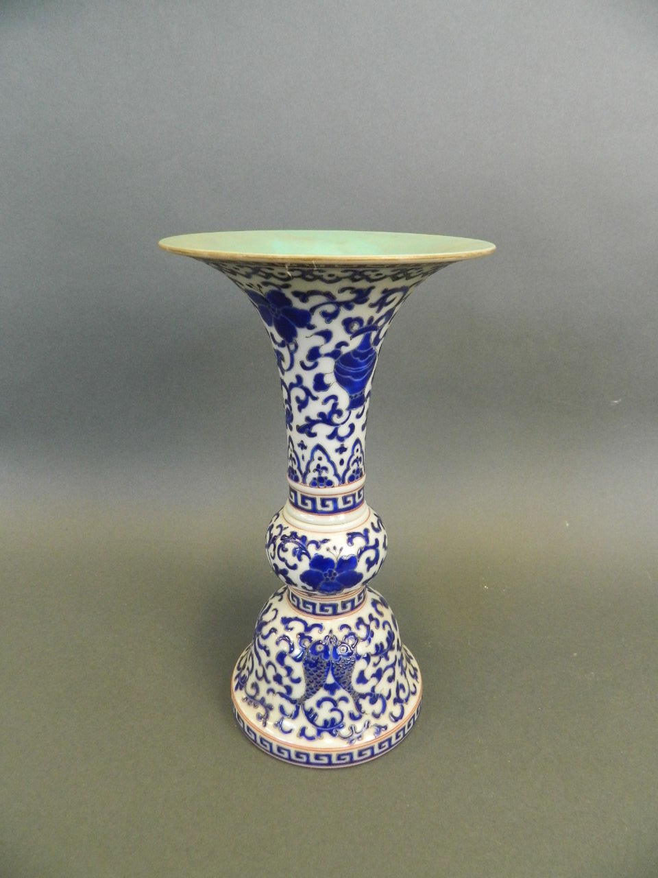 A Chinese porcelain two section Gu shaped vase with scrolling blue enamel lotus flower decoration,