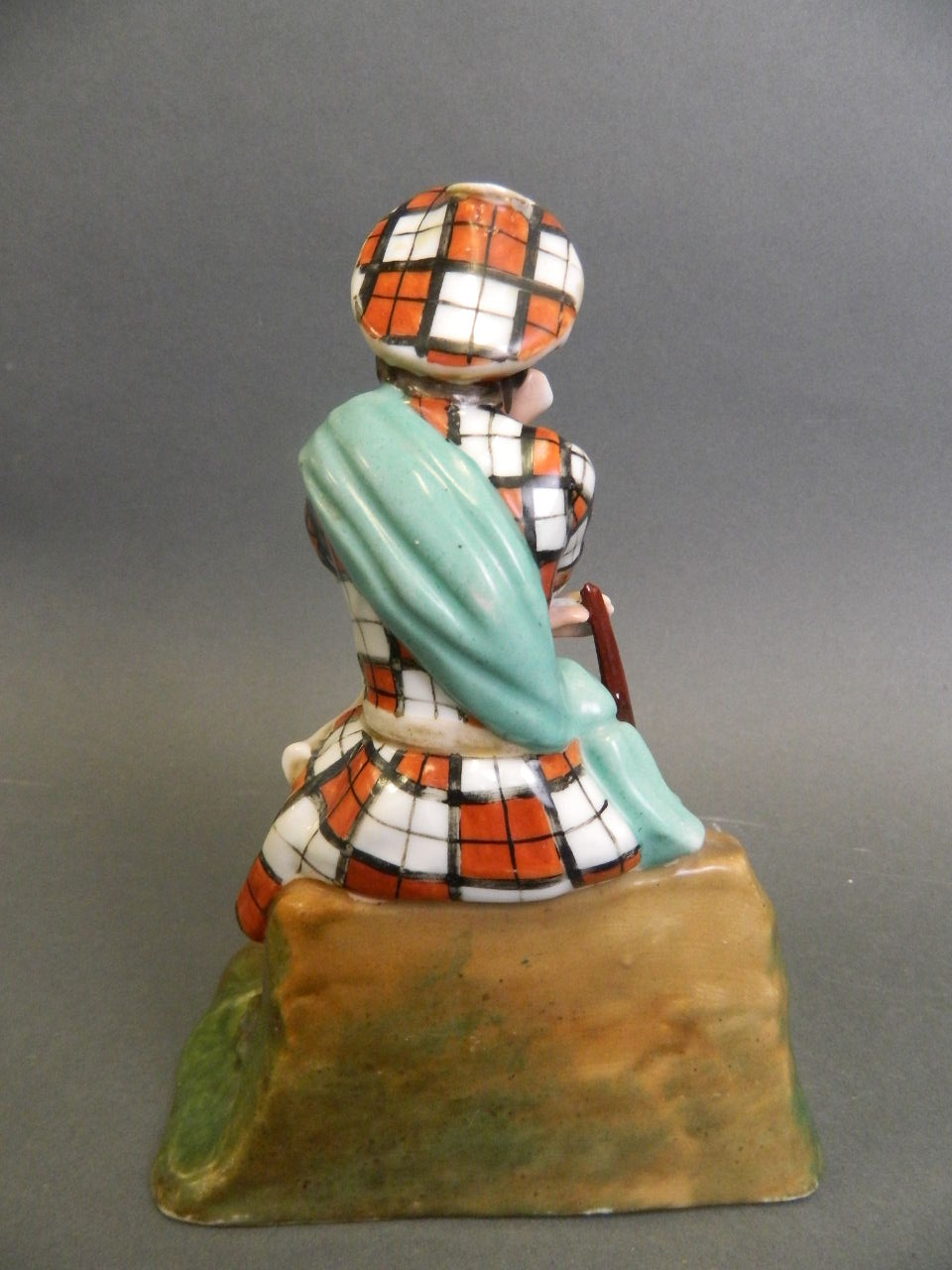 A porcelain figure of a Scottish highlander seated on a rock with a small dog asleep at his feet, - Image 2 of 4