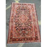 A hand woven Persian village carpet with floral medallion design on an ebony ground, 48" x 75" (