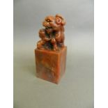 A Chinese marbled chicken blood soapstone seal with carved twin kylin knop and engraved character