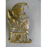 A Victorian brass money clip in the form of Mr Punch seated in an armchair, with detailed engraved