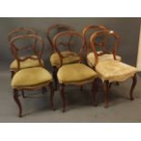 A set of four Victorian walnut balloon back dining chairs with carved backs, raised on cabriole