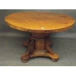 A pine circular topped dining table, raised on an octagonal column and shaped platform with bun