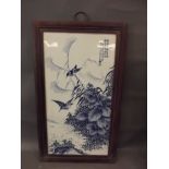 A Chinese blue and white porcelain panel depicting birds amongst foliage, mounted in a hardwood