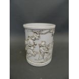 A Chinese white ground porcelain brush pot with relief decoration of boys playing in a garden,