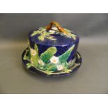 A Majolica cheese dish by George Jones, decorated with flowers and leaves on a blue ground, 8"