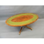 A mahogany oval shaped occasional table with inset leather top, raised on a turned column and