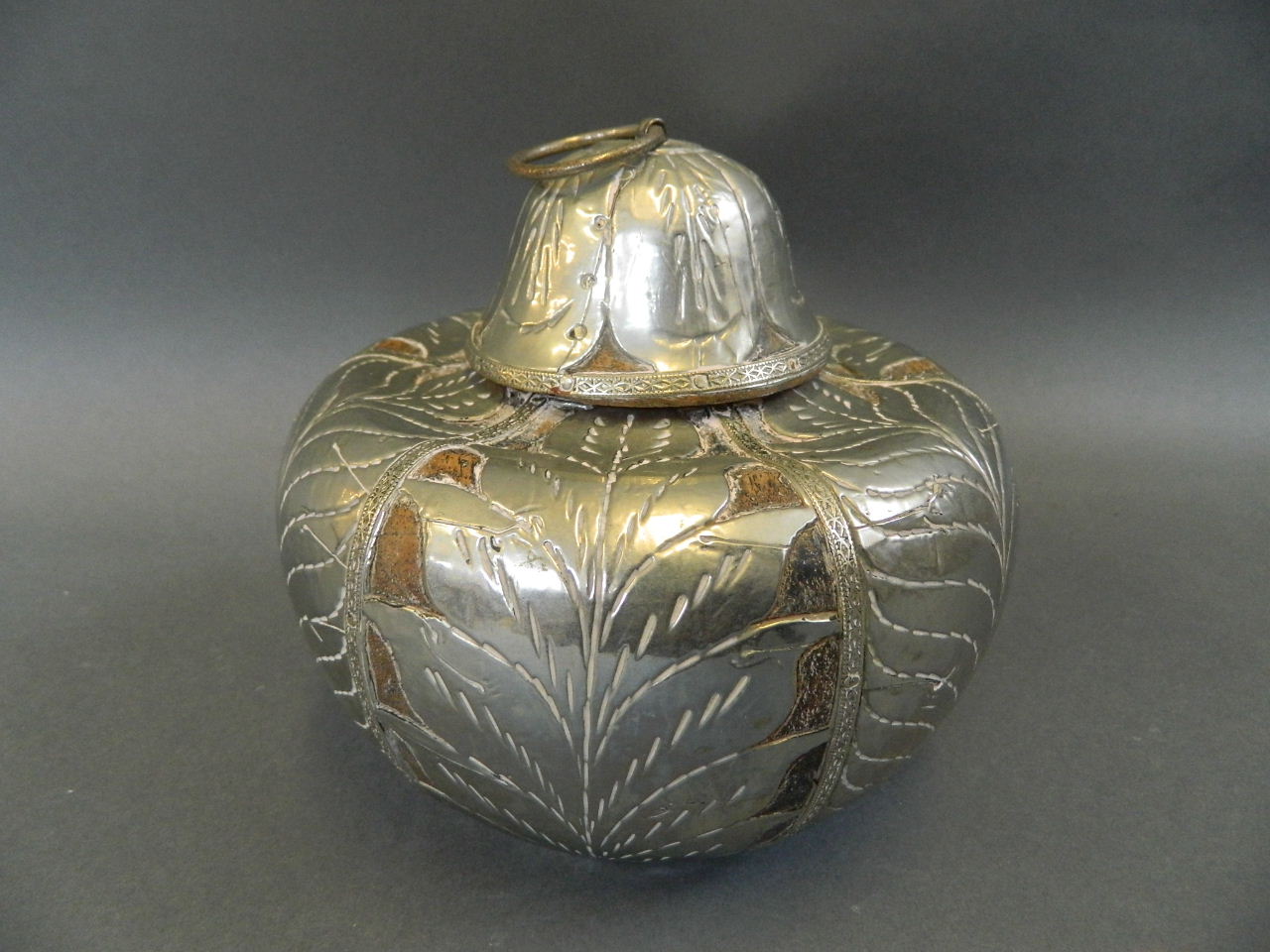 A Middle Eastern wooden pot and cover of squat form with white metal pierced and engraved leaf