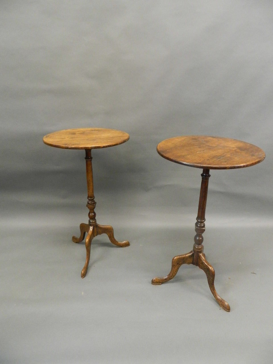 A pair of antique elm occasional tables, raised on turned columns and tripod supports with pad feet,