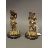 A pair of C19th brass vesta holders in the form of a young fisherman and farmer, mounted on marble