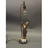 An early C20th bronzed metal table lamp in the form of a young pipe smoker, mounted on a marble