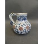 A Chinese Ming style blue and white water jug with scrolling floral decoration and red highlights,