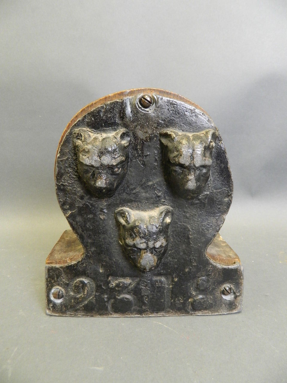 A C19th British painted lead fire insurance plaque decorated with three leopard masks, policy no.