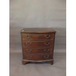 A Georgian style mahogany bow fronted four drawer chest with canted corners, raised on bracket