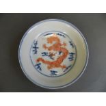A Chinese blue and white porcelain dish with red enamel dragon and flaming pearl decoration, 6