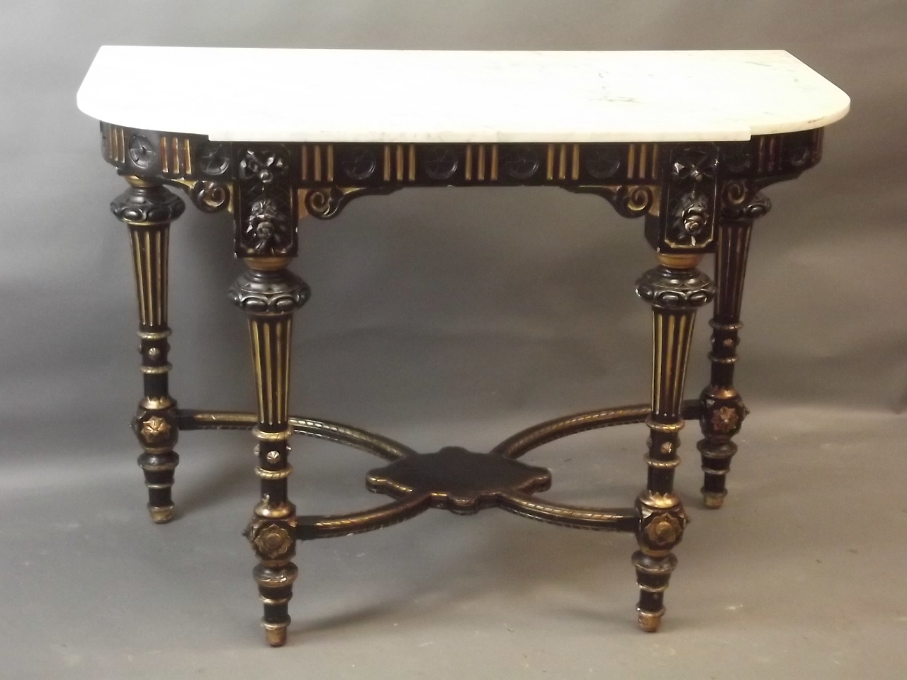 A C19th ebonised and parcel gilt console table with crossed stretchers and undertier, and marble