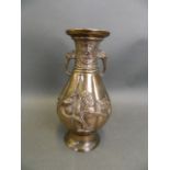 An Oriental bronze ribbed vase with twin elephant mask handles and applied relief decoration of