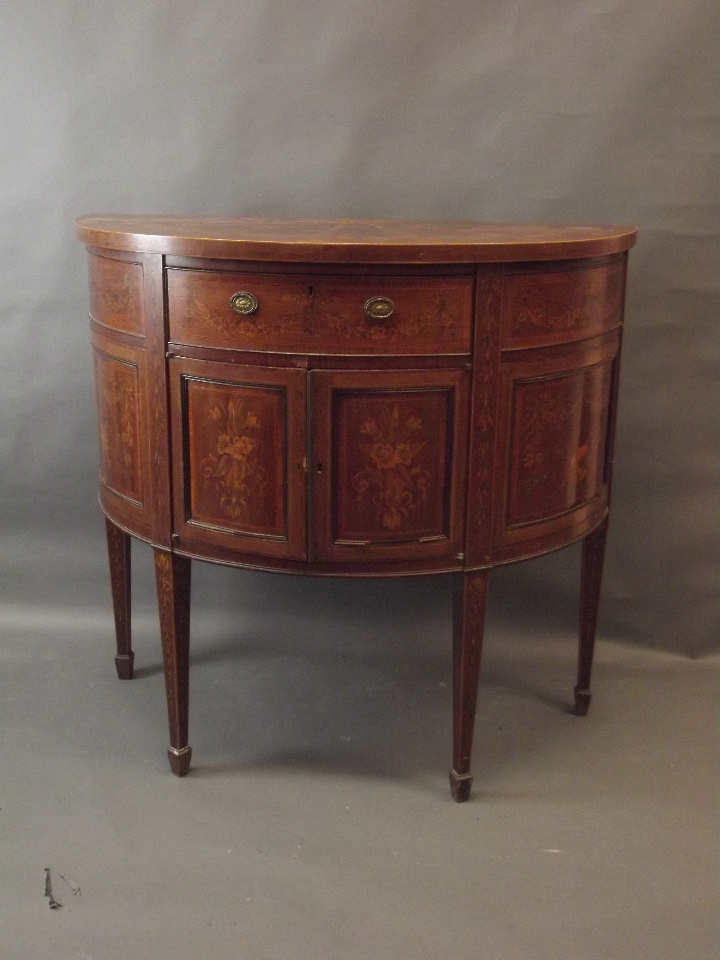 A C19th figured mahogany demi-lune side cabinet with Adam style penwork inlaid decoration of