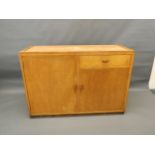 A 'Token Works' satin birch side cabinet of two cupboards and a drawer, the top rebated but lacks