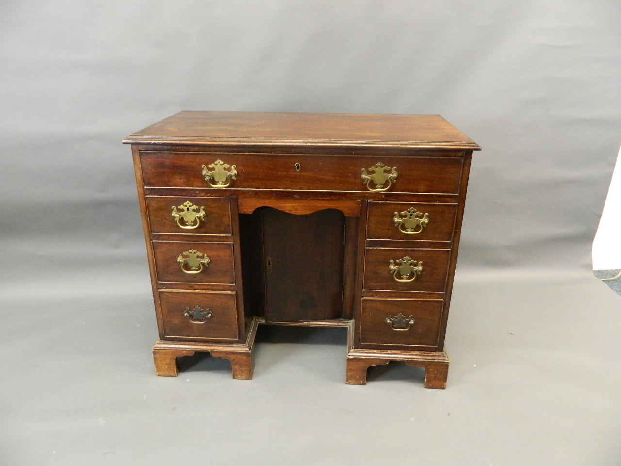 A Georgian mahogany seven drawer kneehole desk with central pigeonhole cupboard and cock beaded