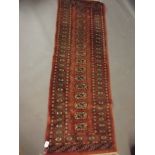 A Turkish hand woven wool runner with medallion design on a rust red field, 24" x 72"