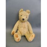 A straw filled plush teddy bear with movable limbs and inset glass eyes, 15" long