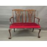 A Victorian Chippendale style two seater settee with carved pierced splat back, raised on cabriole