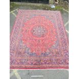 A large antique red ground Persian Kashan carpet with medallion design on a blue field within a