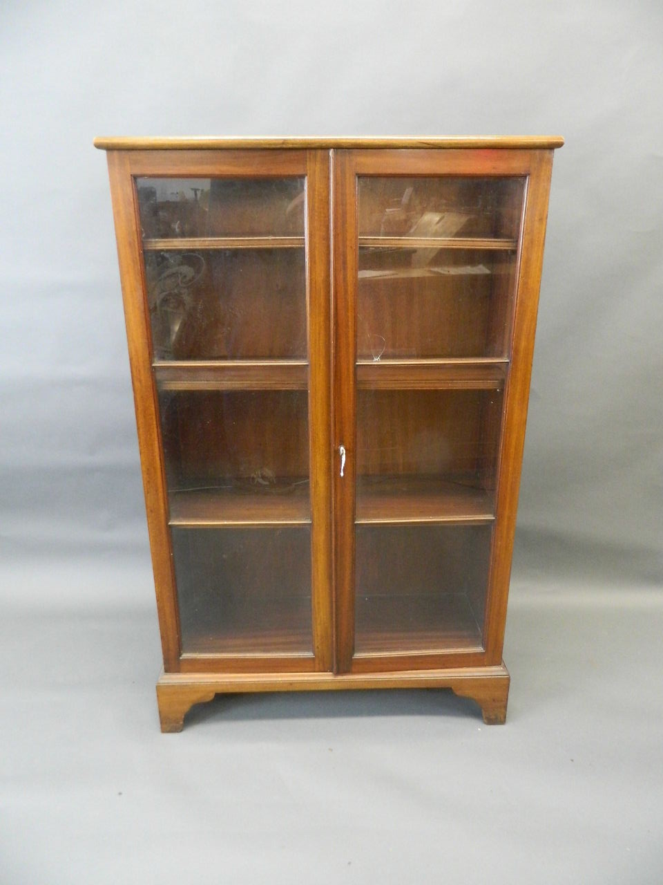 An Edwardian mahogany two door glazed bookcase raised on bracket supports, 30" x 11" x 48" (AF one