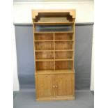 A pine bookcase with a fixed shelf upper section over a base of two cupboards, 48" x 16" x 108"