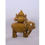 A Chinese ochre glazed porcelain ornament in the form of an elephant carrying a flask, indistinct