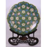 A Chinese cloisonné charger with lobed rim, decorated with trailing flowers on a dark green